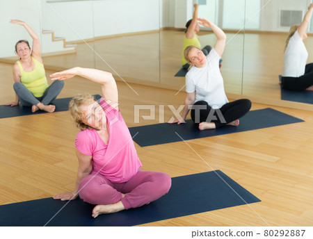 Women exercising during yoga class in fitness center - vakrasana pose 80292887