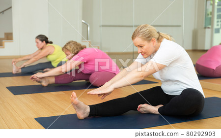 Women are doing head-to-knee pose 80292903