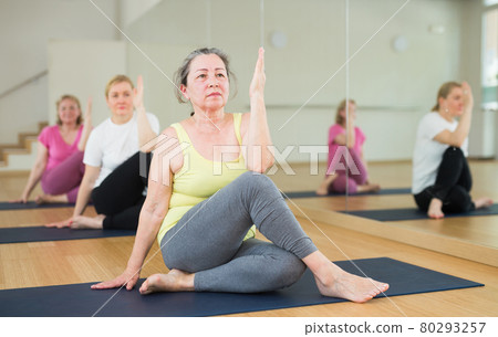 Active elderly woman practicing yoga at group 80293257
