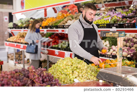 Market worker puts vegetables on the counter 80293466