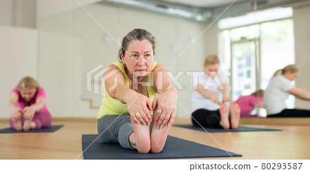 Ladies are doing seating forward bend Ladies are doing seating forward bend 80293587