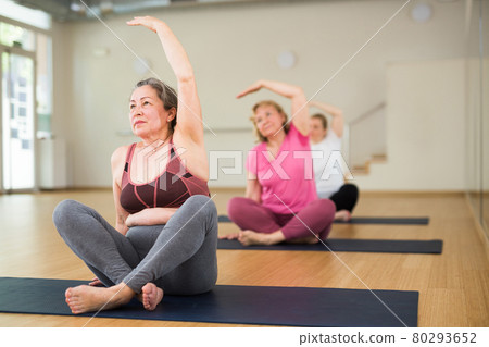 Women exercising during yoga class in fitness center - vakrasana pose Women exercising during yoga class in fitness center - vakrasana pose 80293652