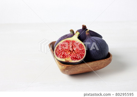 Fresh figs in a wooden bowl on a white background. Food Photo. Purple Fig with red seeds close up. Side view. Fresh figs in a wooden bowl on a white background. Food Photo. Purple Fig with red seeds close up. Side view. 80295595