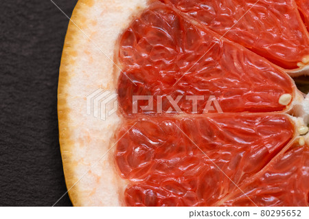 Sliced red grapefruit on black background closeup. Food background. Flat lay. Juicy ripe fresh citrus fruit grapefruit. Top view, macro Sliced red grapefruit on black background closeup. Food background. Flat lay. Juicy ripe fresh citrus fruit grapefruit. Top view, macro 80295652