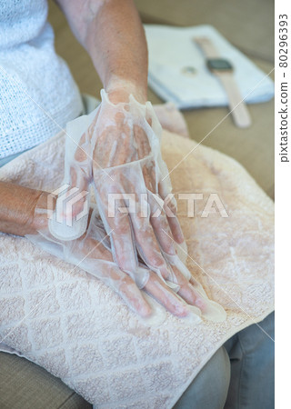 Senior woman wearing hand mask gloves. Moisturizing gloves to soften and protect hand skin. 80296393