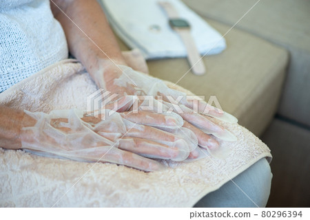 Senior woman wearing hand mask gloves. Moisturizing gloves to soften and protect hand skin. Senior woman wearing hand mask gloves. Moisturizing gloves to soften and protect hand skin. 80296394