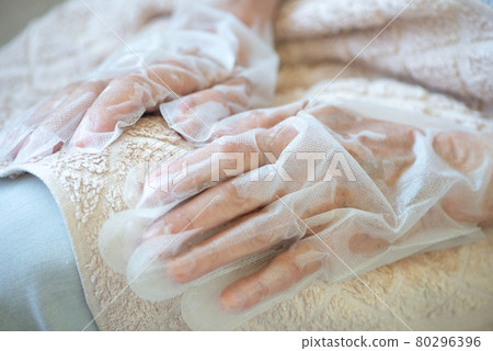 Senior woman wearing hand mask gloves. Moisturizing gloves to soften and protect hand skin. Senior woman wearing hand mask gloves. Moisturizing gloves to soften and protect hand skin. 80296396