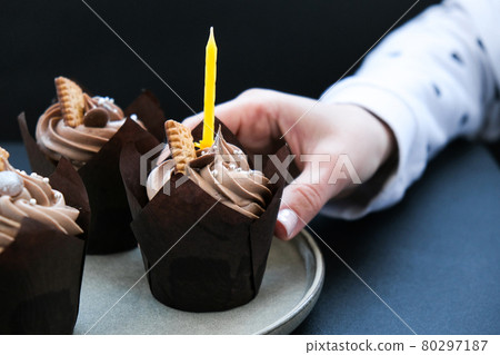 Female hands making Delicious chocolate cupcakes with cream on dark background. Three chocolate muffin. Birthday cake party preparation Female hands making Delicious chocolate cupcakes with cream on dark background. Three chocolate muffin. Birthday cake party preparation 80297187