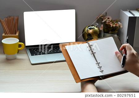Businessman holding notebook and using laptop computer at home office. Businessman holding notebook and using laptop computer at home office. 80297651