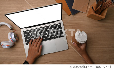 Overhead shot woman holding coffee cup and using laptop computer. Overhead shot woman holding coffee cup and using laptop computer. 80297681