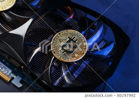 Video card with a gold coin Bitcoin on the cooler close-up. 80297992