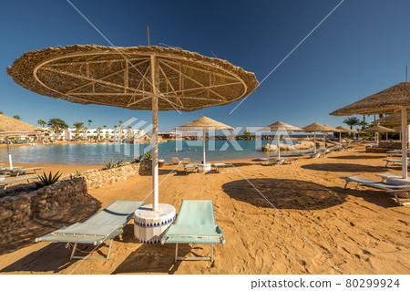 Straw umbrellas and sunbeds on the wonderful tropical beach. Straw umbrellas and sunbeds on the wonderful tropical beach. 80299924