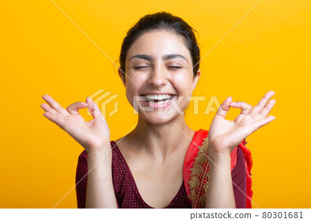 Portrait of young adult indian woman in sari meditating zen like with ok sign mudra gesture Portrait of young adult indian woman in sari meditating zen like with ok sign mudra gesture 80301681