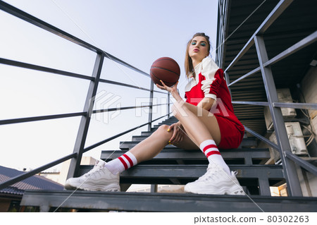 Beautiful adorable young girl in retro 90s fashion style, outfits posing on stairs, outdoors. Concept of eras comparison, beauty, fashion and youth. Beautiful adorable young girl in retro 90s fashion style, outfits posing on stairs, outdoors. Concept of eras comparison, beauty, fashion and youth. 80302263