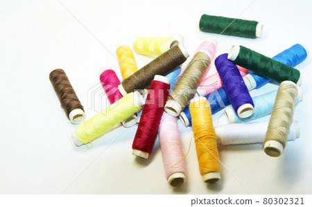 Up of colorful hand-sewn threads that roll casually on the cloth Up of colorful hand-sewn threads that roll casually on the cloth 80302321