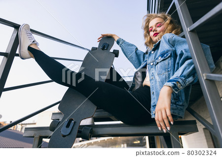 Beautiful adorable young girl in retro 90s fashion style, outfits posing on stairs, outdoors. Concept of eras comparison, beauty, fashion and youth. Beautiful adorable young girl in retro 90s fashion style, outfits posing on stairs, outdoors. Concept of eras comparison, beauty, fashion and youth. 80302324