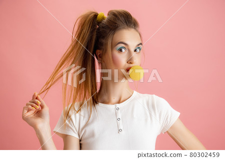 Portrait of adorable pretty young girl in retro 90s fashion style, outfits posing isolated over pink studio background. Concept of eras comparison, beauty, fashion and youth. Portrait of adorable pretty young girl in retro 90s fashion style, outfits posing isolated over pink studio background. Concept of eras comparison, beauty, fashion and youth. 80302459