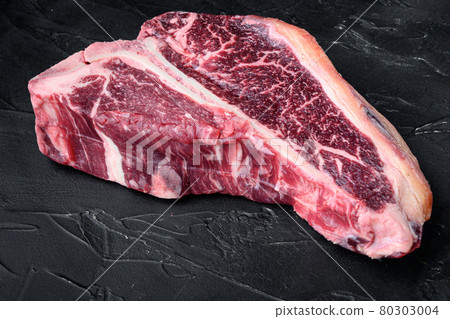 Dry-aged Raw T-bone or porterhouse beef marbled meat prime steak, on black stone background 80303004