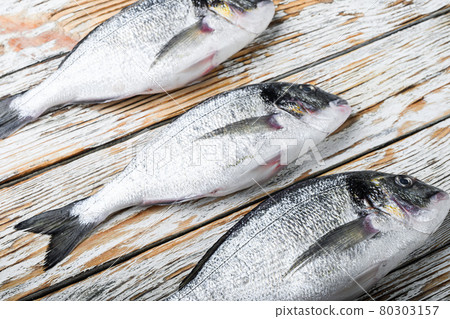 Set of raw headof dorado or Gilt head bream fish over white wood table side view. 80303157