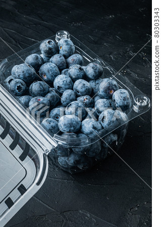 Organic blueberries in plastic box package, on black background Organic blueberries in plastic box package, on black background 80303343