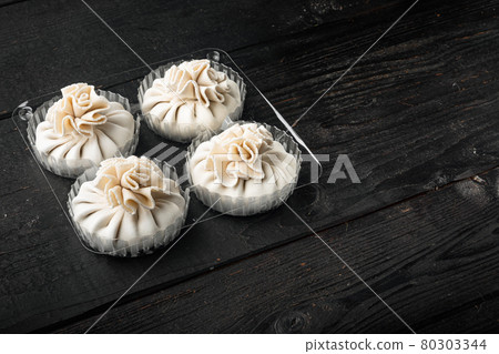 Delicious baozi, Chinese steamed meat bun, in plastic tray, on black wooden table background, with copy space for text Delicious baozi, Chinese steamed meat bun, in plastic tray, on black wooden table background, with copy space for text 80303344