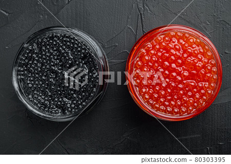 Glass jars with black and red caviar, on black background, top view flat lay Glass jars with black and red caviar, on black background, top view flat lay 80303395