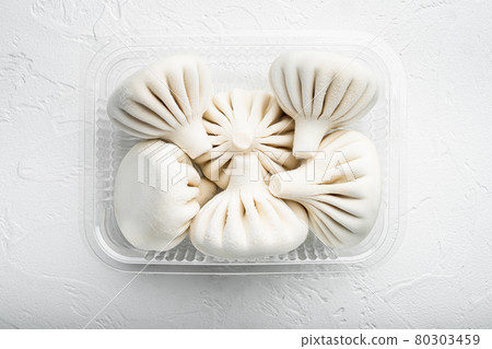 Khinkali Dumplings with beef and lamb meat, in plastic tray, on white stone surface, top view flat lay Khinkali Dumplings with beef and lamb meat, in plastic tray, on white stone surface, top view flat lay 80303459