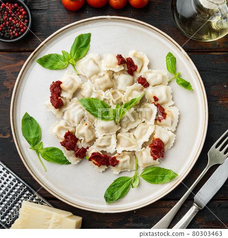 Ravioli pasta with mushroom cream sauce and cheese - Italian food style with basil parmesan and tomatoe on white plate on old dark wooden table background , top view flat lay 80303463