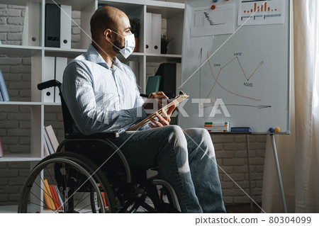 Disabled young man making presentation in office wearing medical mask Disabled young man making presentation in office wearing medical mask 80304099