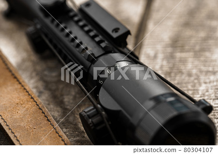 The optical sight and shotgun on wooden backgorund The optical sight and shotgun on wooden backgorund 80304107