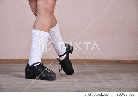 Close-up of female legs in black leather shoes dancing national Irish dances. Close-up of female legs in black leather shoes dancing national Irish dances. 80305456