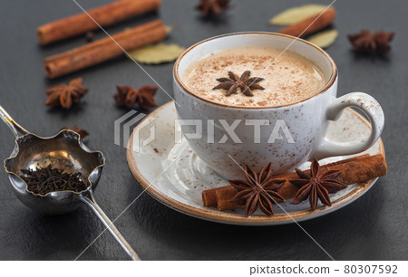 Indian Masala chai tea. Traditional Indian hot drink with milk and spices on dark stone background closeup. 80307592
