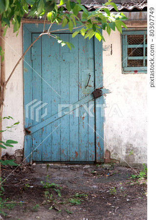 Closed wooden door with a lock the entrance to an old abandoned village barn Closed wooden door with a lock the entrance to an old abandoned village barn 80307749