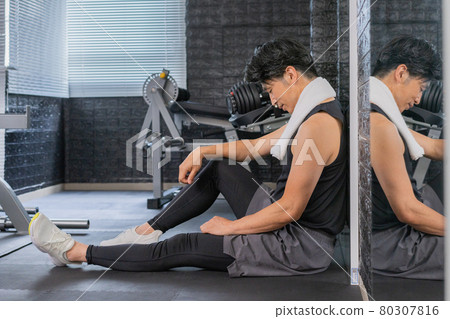 Middle-aged man sitting on the floor at the gym 80307816