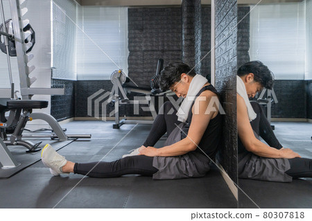 Middle-aged man sitting on the floor at the gym 80307818