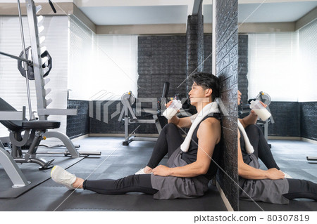 Middle-aged man sitting on the floor at the gym 80307819