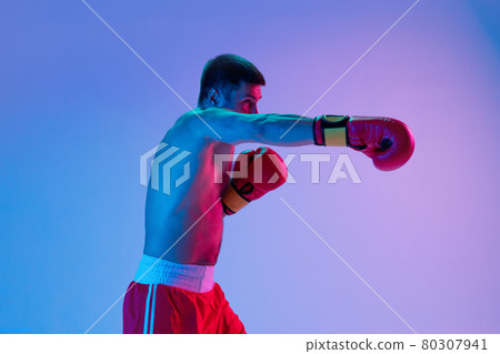 One man, professional boxer in sportwear boxing on studio background in gradient neon light. Concept of sport, activity, movement, wellbeing. 80307941