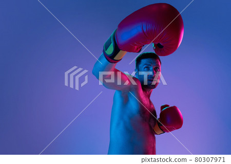 Close-up professional boxer in sportwear boxing on studio background in gradient neon light. Concept of sport, activity, movement, wellbeing. Close-up professional boxer in sportwear boxing on studio background in gradient neon light. Concept of sport, activity, movement, wellbeing. 80307971