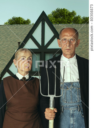 Elderly man and woman in art performance, replica of painting american gothic. Retro style, comparison of eras and cultural concept. Elderly man and woman in art performance, replica of painting american gothic. Retro style, comparison of eras and cultural concept. 80308873