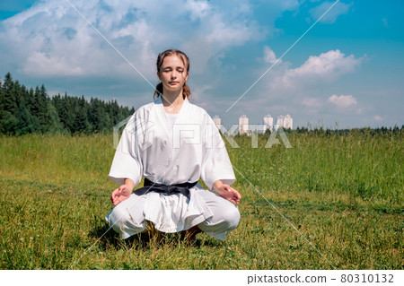 teenage girl karateka before starting training outdoor enters the mokuso meditative state in the seiza pose teenage girl karateka before starting training outdoor enters the mokuso meditative state in the seiza pose 80310132