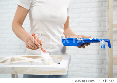 Close up of woman painting wooden storage stand 80310232