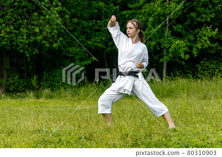 teenage girl training karate kata outdoors, performs age-uke (rising or upward block) teenage girl training karate kata outdoors, performs age-uke (rising or upward block) 80310903