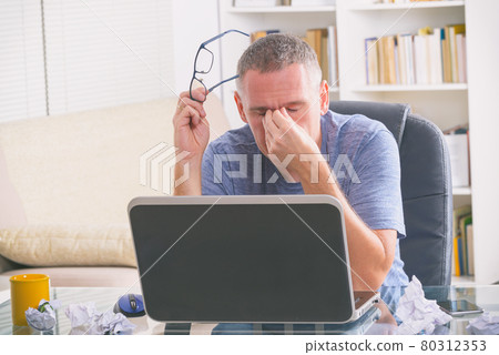 Tired freelancer man rubbing his eye 80312353