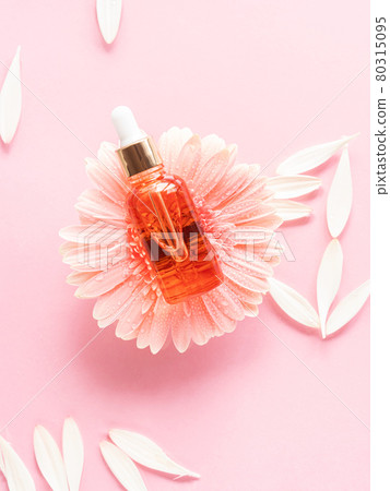 Cosmetic beauty serum oil acid bottle product on pink background with pink daisy 80315095