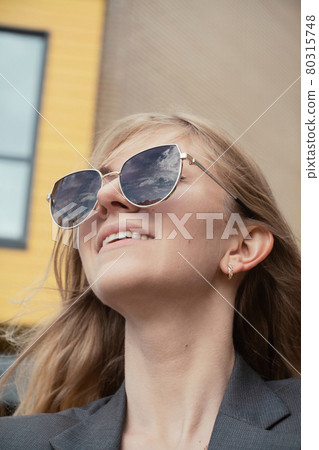 Portrait of young cheerful woman in sunglasses reflecting clouds Portrait of young cheerful woman in sunglasses reflecting clouds 80315748