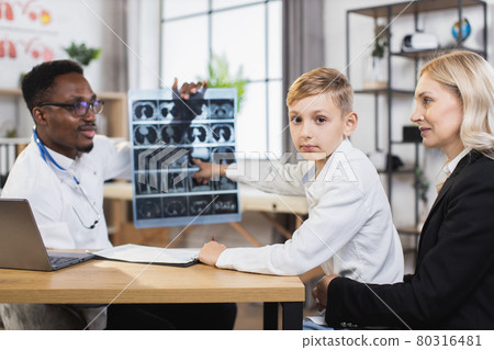 African doctor showing x ray results for woman with son 80316481