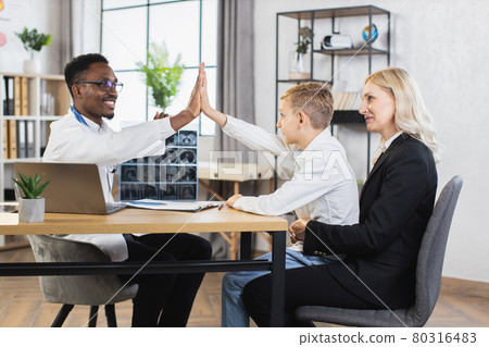 Cute caucasian boy giving high five to african doctor Cute caucasian boy giving high five to african doctor 80316483