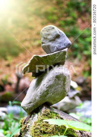 Rock pyramid, rock balancing art. Close-up of a stack of stones in perfect balance in a mountain forest. Sun rays. Meditation, balance, peace. Hobby. Vertical photo. Rock pyramid, rock balancing art. Close-up of a stack of stones in perfect balance in a mountain forest. Sun rays. Meditation, balance, peace. Hobby. Vertical photo. 80316720