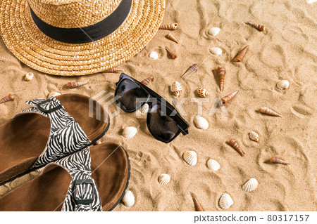 Summer beachwear, flip flops, hat, sunglasses and seashells on sand beach. Summer beachwear, flip flops, hat, sunglasses and seashells on sand beach. 80317157