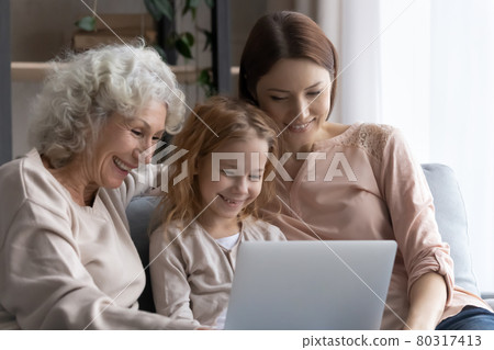 Little girl watching movie on laptop with grandma and mom Little girl watching movie on laptop with grandma and mom 80317413